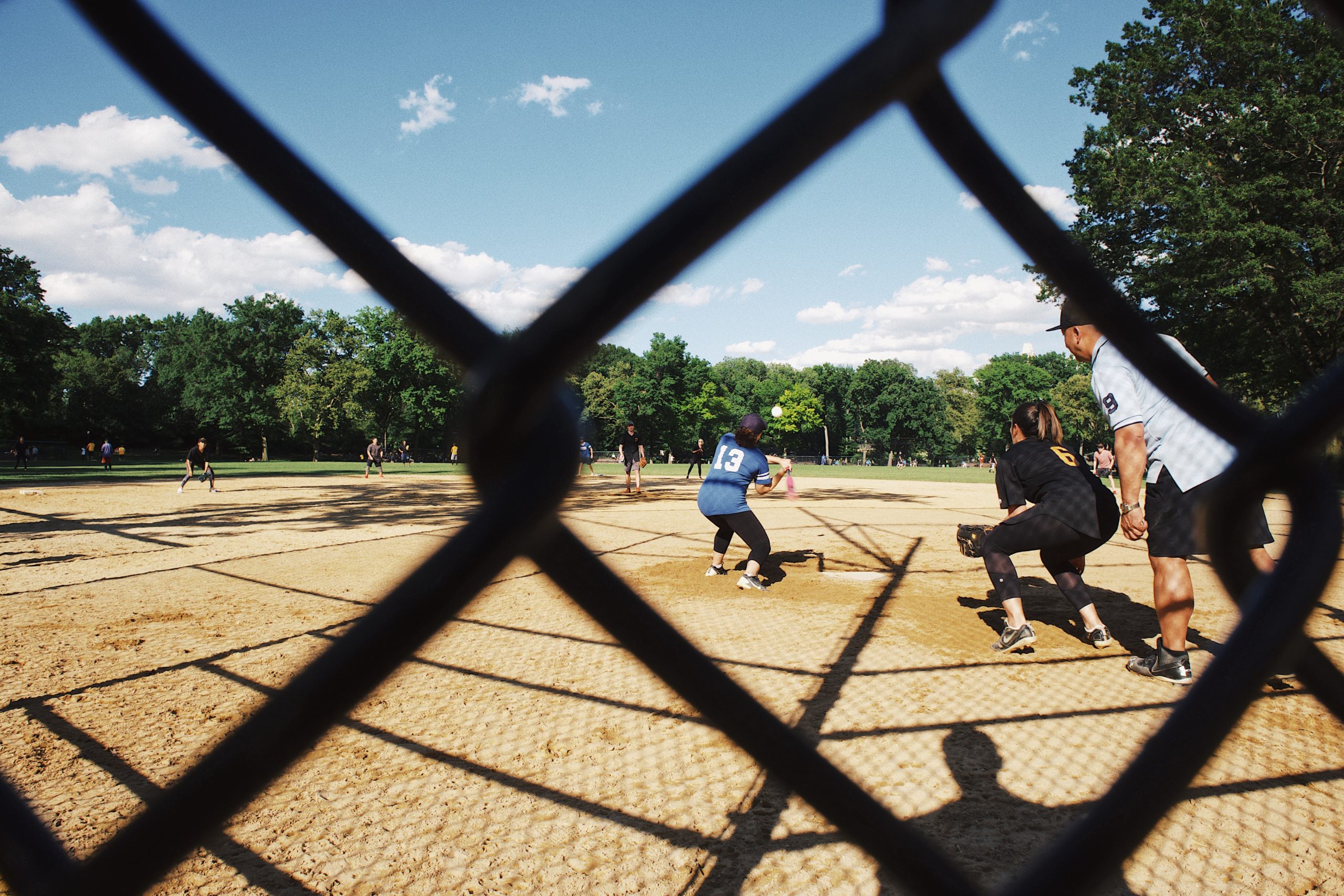 gray cyclone fence across people playing baseball